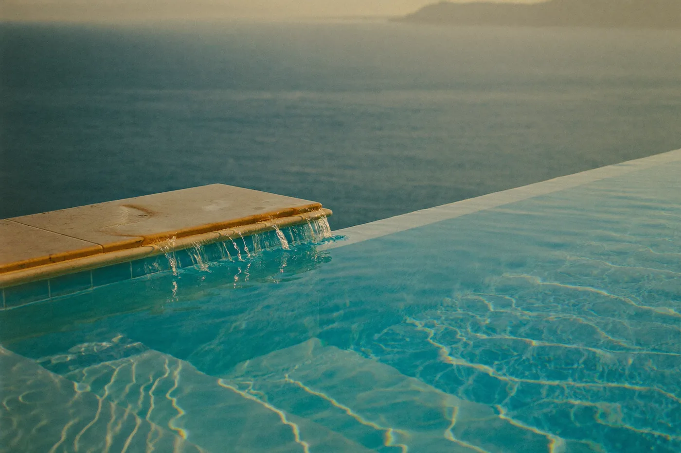Infinity pool edge meeting the sea at golden hour