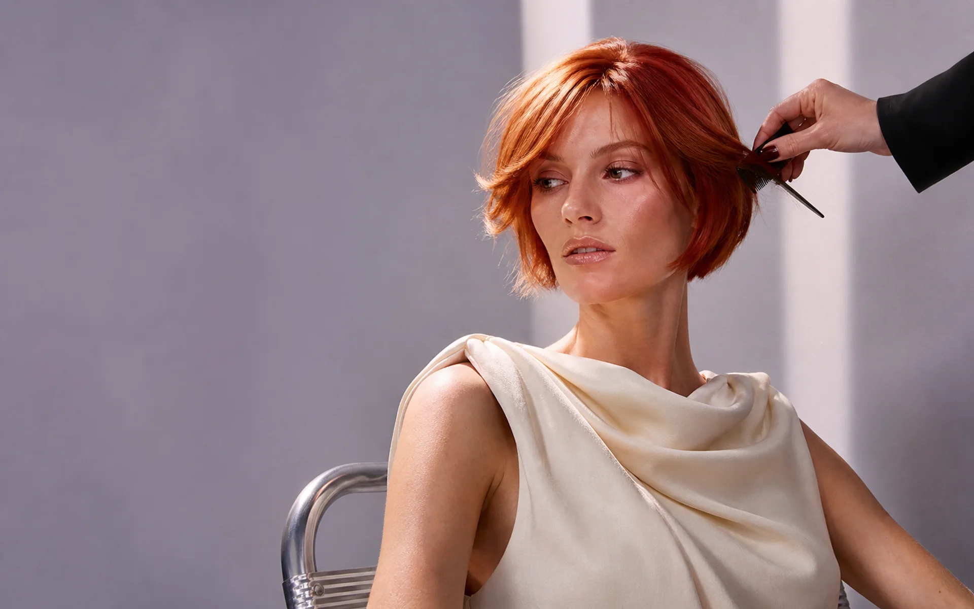 Copper-red bob mid-finish, stylist combing through